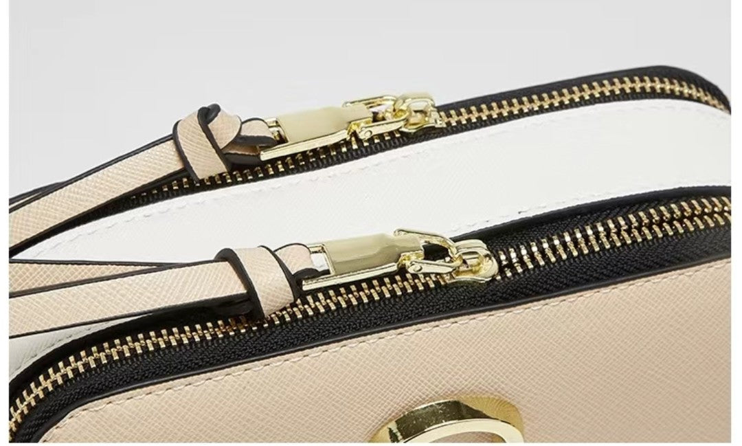 Close-up of a beige handbag with gold zipper and clasp on a light gray background