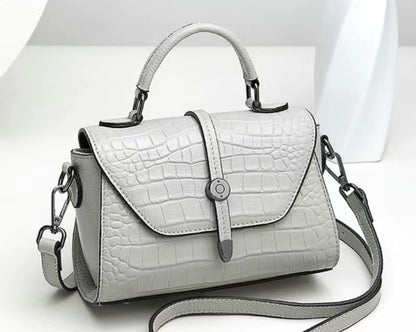 White handbag with crocodile texture on a white background