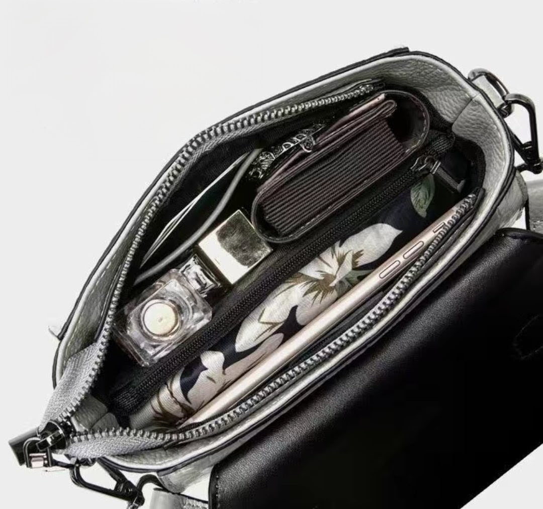 Open black handbag revealing a floral-patterned item inside on a light gray background