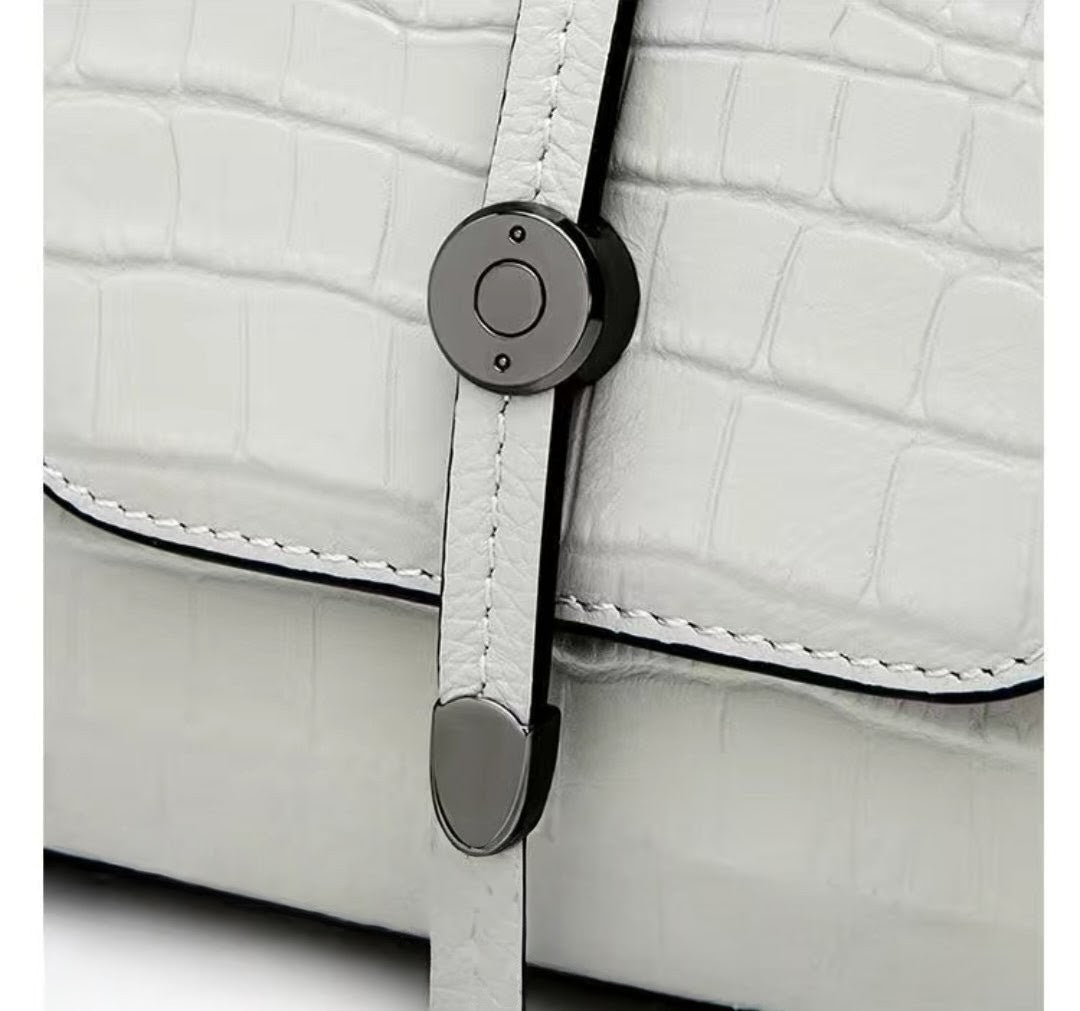 Close-up of a white textured bag with a black strap and silver buckle.