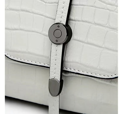 Close-up of a white textured bag with a black strap and silver buckle.