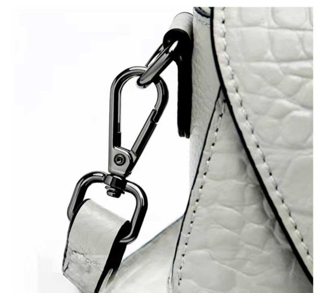 Close-up of a white textured handbag with a metal clasp on a white background