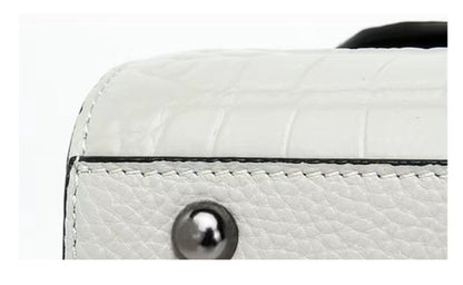 Close-up of a white textured handbag with a metallic button on a white background