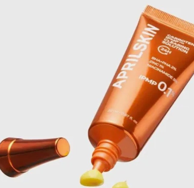 Orange skincare tube with 'APRILSKIN' branding on a light gray background