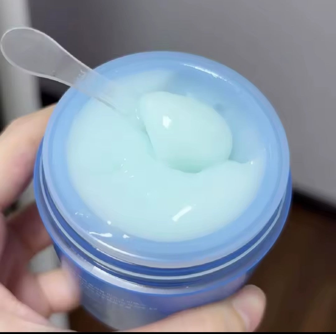 Jar of blue gel with a spoon inside, held by a hand.