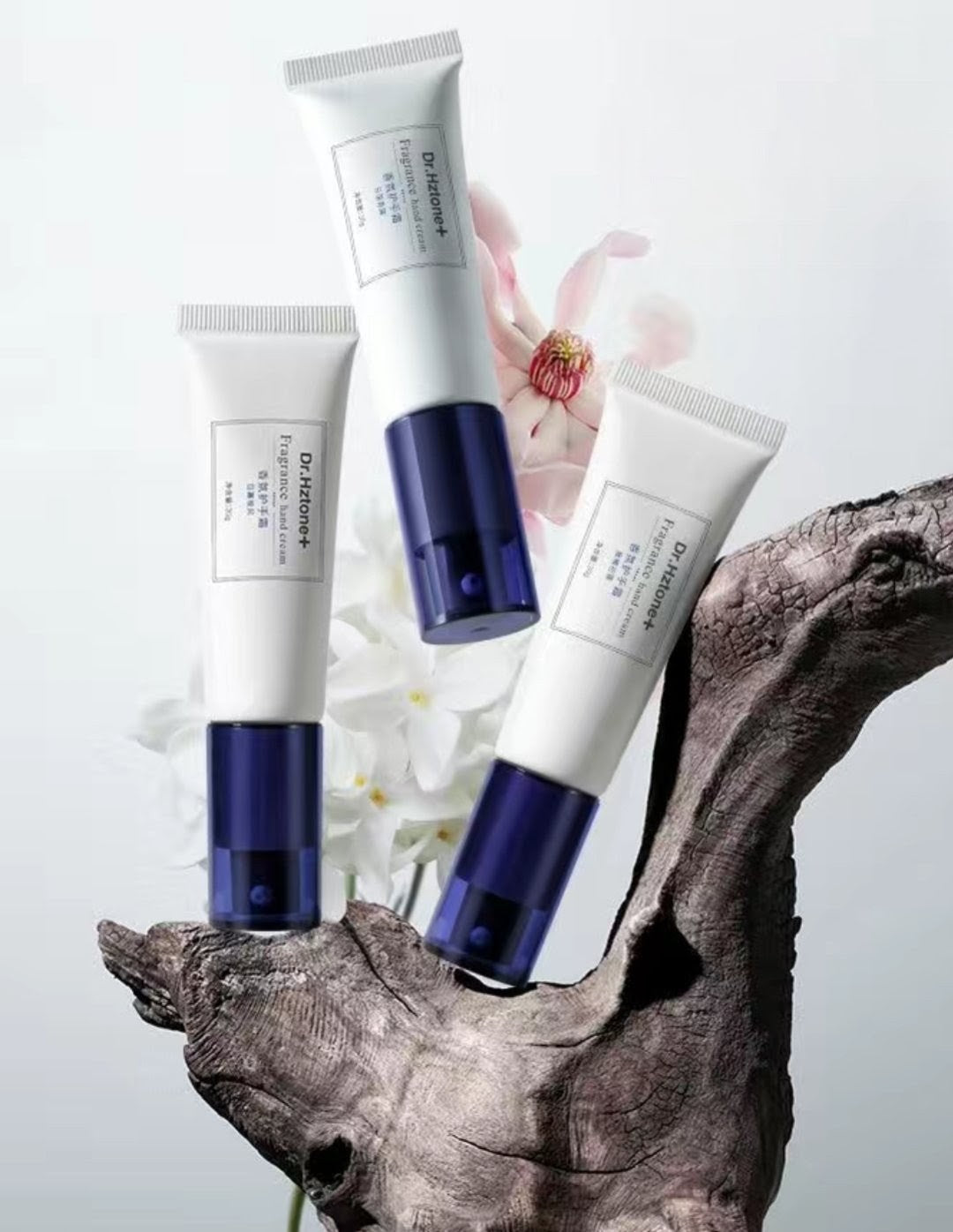 Three skincare products with blue and white packaging on a natural wood and flower background
