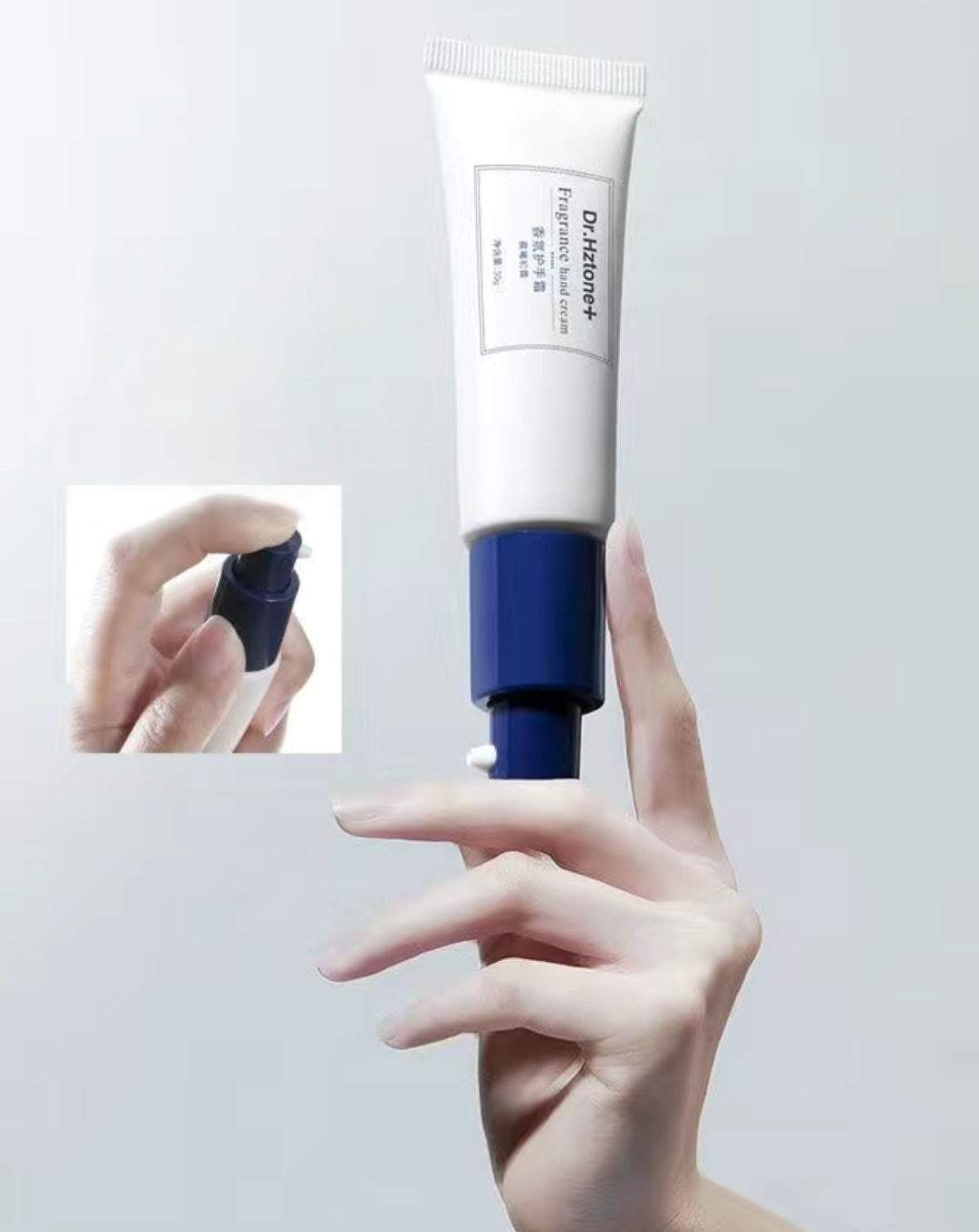 Hand holding a tube of skincare product with close-up inset on a light gray background