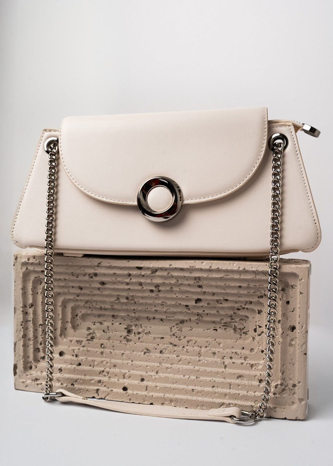 Beige handbag with cork-textured base and chain strap on a light gray background