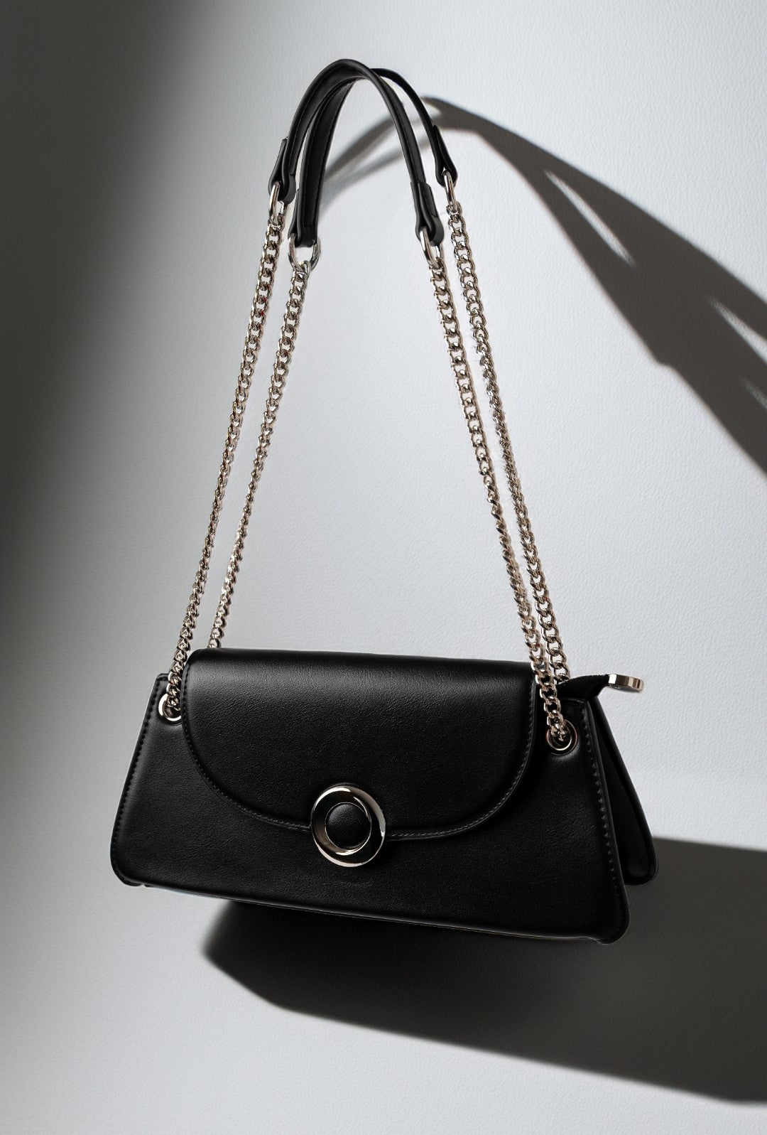 Black handbag with chain strap on a gradient gray background