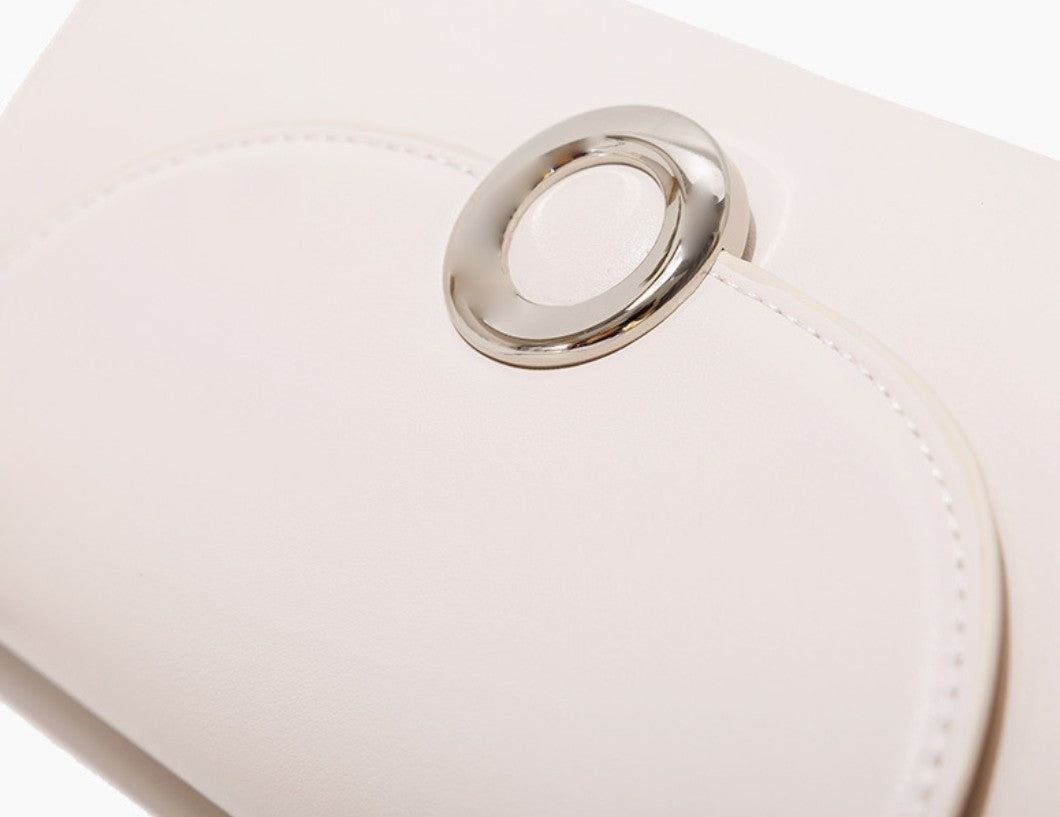 Close-up of a white handbag with a silver ring handle on a white background
